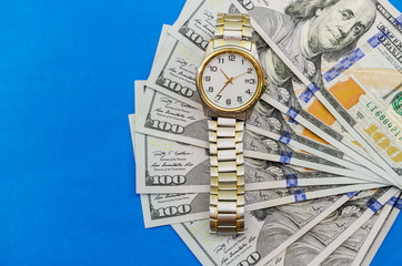 wrist watch on dollars on blue background close up