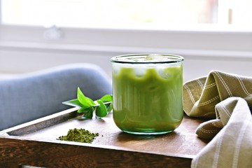 Glass of iced matcha green tea latte on the light home background 