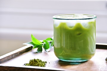 Glass of iced matcha green tea latte on the light home background 