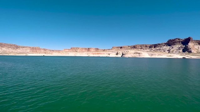 Pan across the sandstone buttes from the turquoise waters of the shore of Lake Powell, Page Arizona.