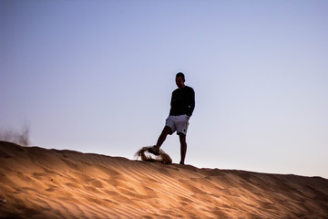 Dark silhouette of a man walking at the desert dunes. Dawn time