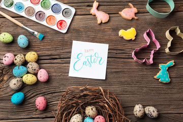 Colorful easter eggs and brushes on wooden table. Top view
