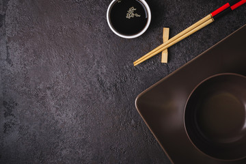 Brown bowls, soy sauce and bamboo chopsticks. Asian table setting