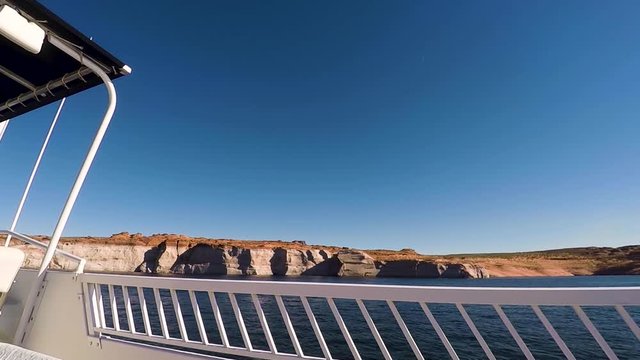 From the deck of a houseboat, the blue waters and sandstone buttes pass by, Lake Powell, Page, ​Arizona