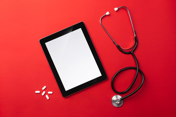 Stethoscope in doctors desk with digital tablet and pills