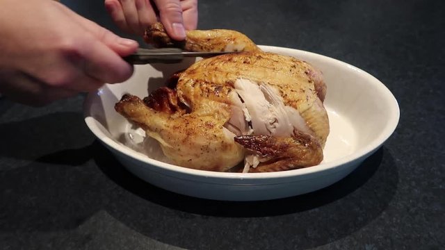 Man cutting or carving a hot roast chicken