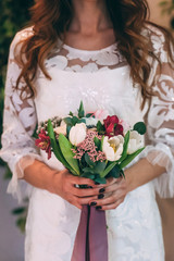 Bride in white wedding dress with a beautiful bouquet of roses