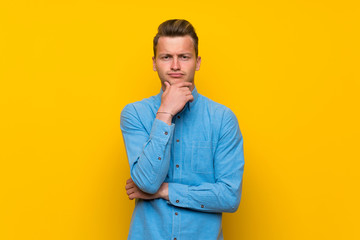 Blonde man over isolated yellow wall thinking