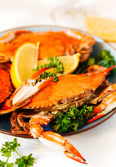 Cooked crabs served on plate with lemon and parsley.