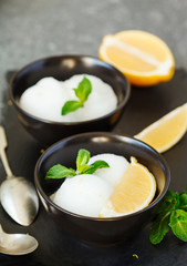 Lemon ice cream in black bowl.