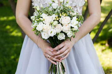 Bride in white wedding dress with a beautiful bouquet of roses