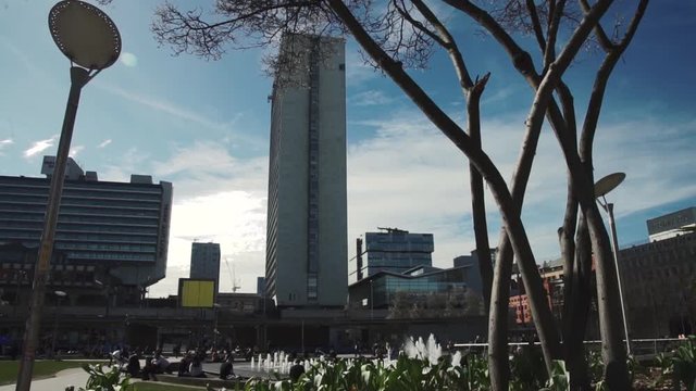 Tower in city on sunny day with greenery/foliage in foreground
