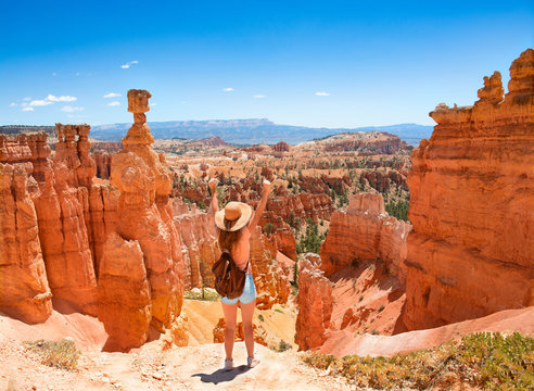 Girl With Raised Hands Relaxing On Top Of The Mountain, Looking At Beautiful Mountain View.Young Woman Standing Next To Thor's Hammer Hoodoo With Raised Hands. Bryce Canyon National Park, Utah, USA