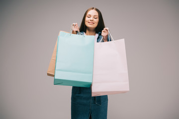 Fototapeta na wymiar smiling and beautiful woman with closed eyes holding shopping bags