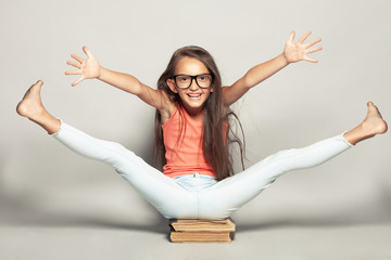 Waiting for the rest concept. Portrait of a happy funny girl after sitting on manuels with legs and hands up over light gray background in summer season casual clothing. Studio shot