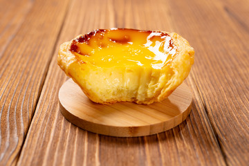fresh portuguese egg tart with a bite on a wood table
