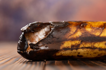 overripe banana with the tip damaged close up on a wood table