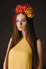 beautiful and brunette woman in elegant dress and wreath looking away isolated on black