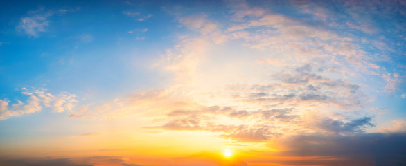 Naklejka na ściany i meble Panorama Sky blue and orange light of the sun through the clouds in the sky