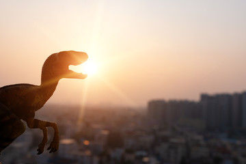 silhouette of velociraptor and buildings in sunset time