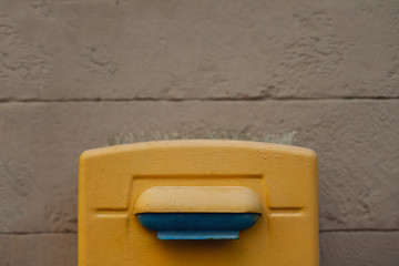 Close up outdoor shot of yellow metal post-box on city wall