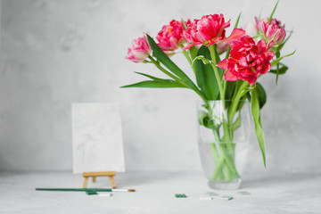 Vase with tulip flowers ,paintbrush with color on a canvas painting and mosaic on gray backround.