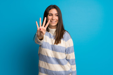 Young woman over blue wall happy and counting four with fingers