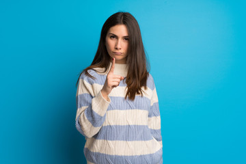 Young woman over blue wall frustrated and pointing to the front