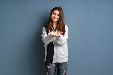 Young sport woman holding copyspace imaginary on the palm to insert an ad