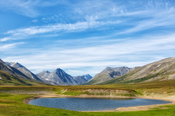 Landscape with a lake in the foreground, chums and mountains on a summer day