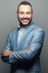 Fototapeta premium Portrait of funny smiling man working as anchorman, standing and posing against gray background. Studio shot