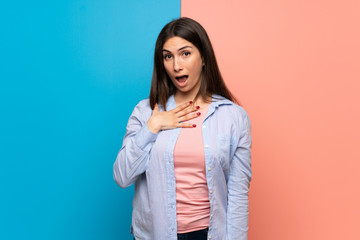 Young woman over pink and blue wall surprised and shocked while looking right