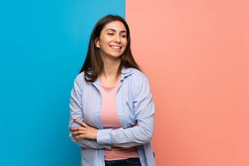 Young woman over pink and blue wall smiling