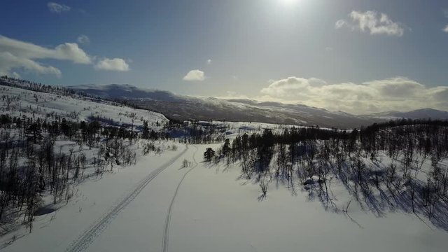 drone footage of beautiful mountain scenery,snow trees all over the place,icy peaks,winter white sunlight lighting up,and clouds that giving life to the whole epic scene. norway getaway in 4K 30fps