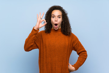 Dominican woman with curly hair surprised and showing ok sign