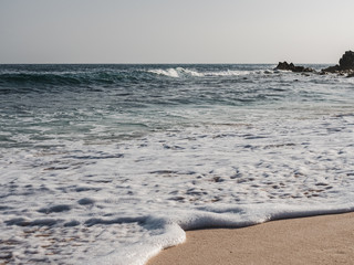 Empty beach against the clear sky and sea waves. Oman, Salalah. Concept of leisure and travel