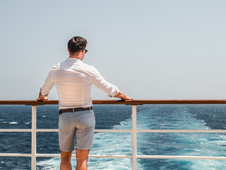 Fashionable man on the empty deck of a cruise liner against the backdrop of the sea waves. Side...