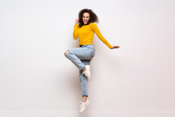 Dominican woman with curly hair jumping over isolated white background