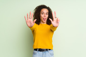 Dominican woman over isolated green background counting eight with fingers