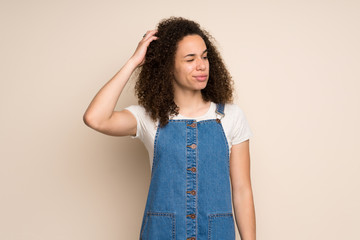 Dominican woman with overalls having doubts while scratching head