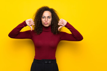 Dominican woman with turtleneck sweater showing thumb down with both hands