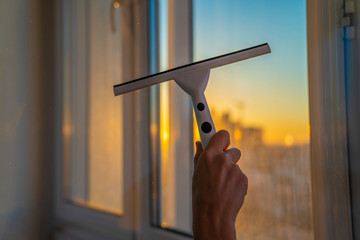 Window cleaner using a squeegee to wash a windows. Hand holding or using window cleaning squeegee,...