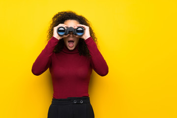 Dominican woman with turtleneck sweater and looking in the distance with binoculars