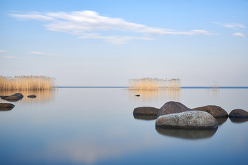 The minimalist background of the sky is reflected in the calm smooth water of the lake.