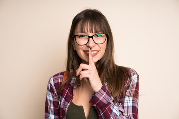 Young woman on ocher background doing silence gesture