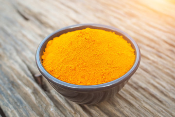 Turmeric powder in black bowls on old wooden table. herbal