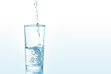 Pouring water into glass on white background. Photo with copy space.