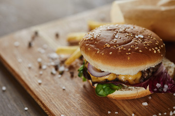 selective focus of salt, pepper, french fries and delicious burger on wooden surface
