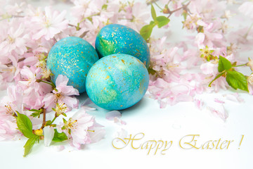 Easter greetings in English. Painted eggs with flowering twigs on a light background. Spring and holidays.