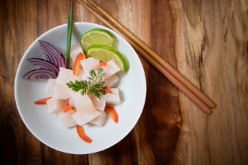 Traditional Ceviche bowl with white fish. Top view on wooden background.